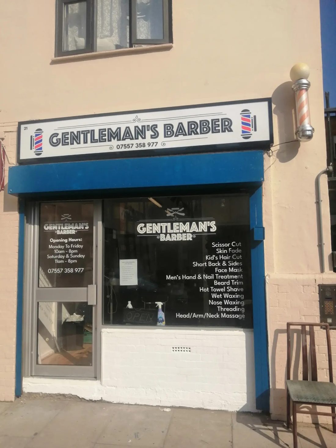 The Gentleman's Barber shopfront on Henriques Street, Whitechapel — navy-trimmed windows with the shop name, a barber's pole and the services list.